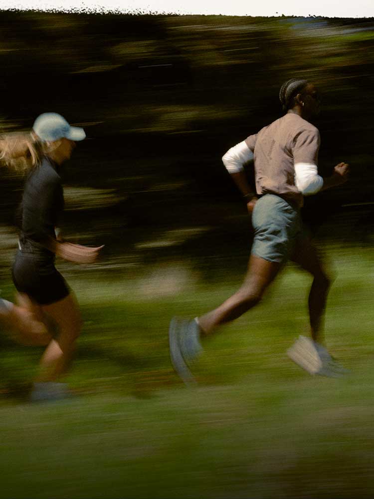Two people running across a green field